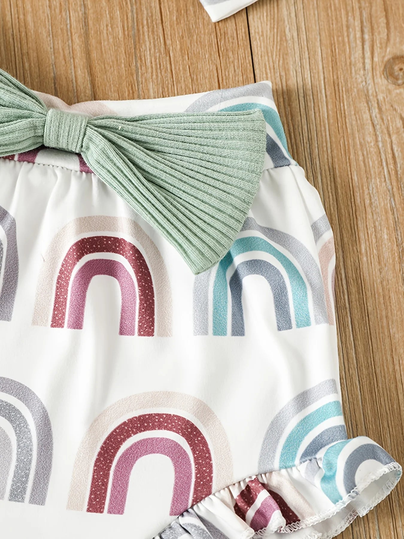 Baby outfit with rainbow pattern and green bow