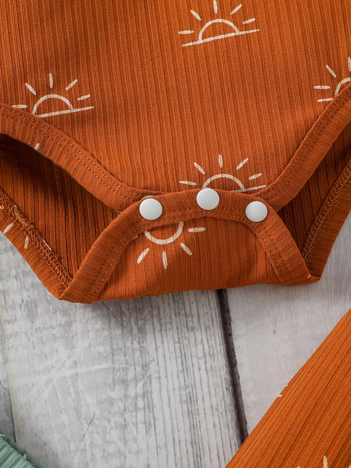 Orange baby onesie with sun patterns