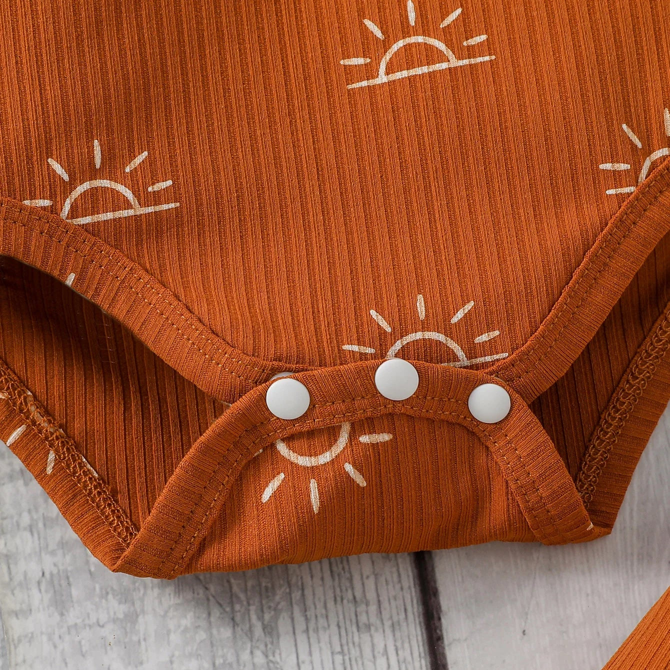 Orange baby onesie with sun patterns