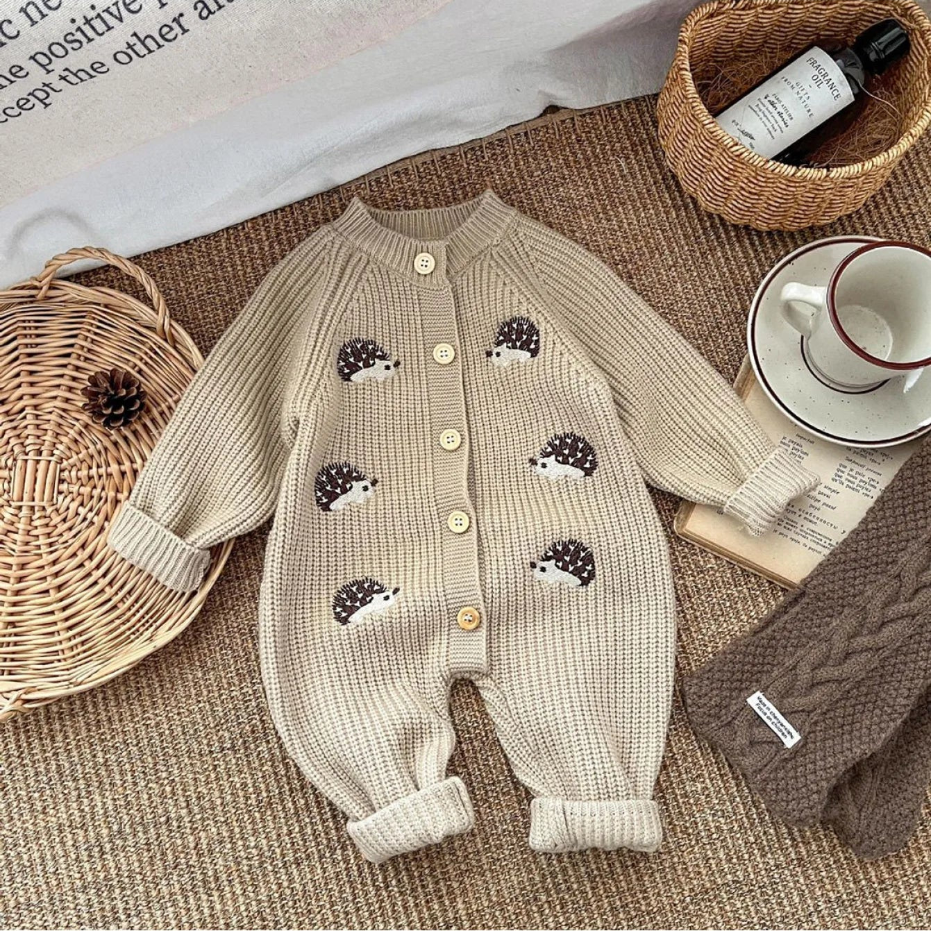 Beige knitted baby romper with hedgehog designs