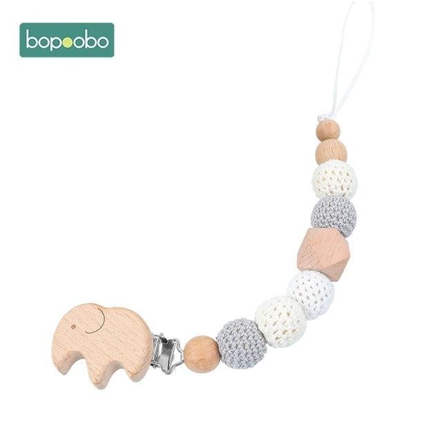 Grey and white knitted balls with wooden elephant on a dummy chain clip
