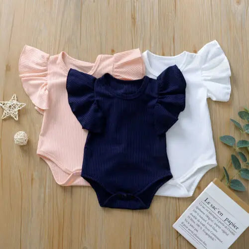 Three baby rompers in pink, navy, and white