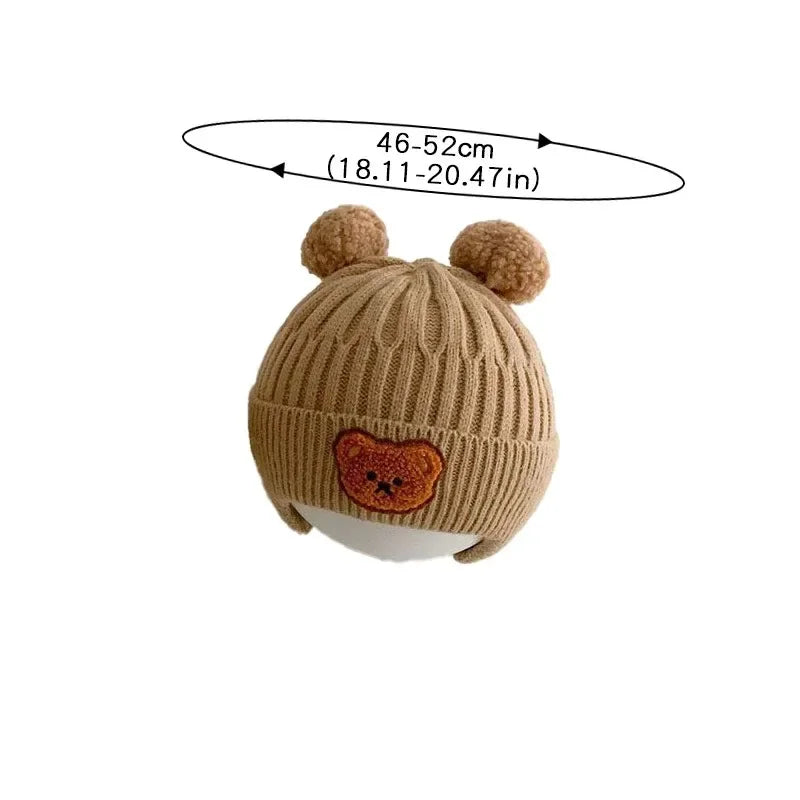 Brown knit baby hat with bear face design and pom-poms