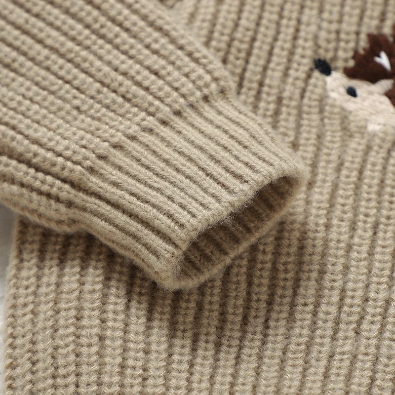 Close-up of a beige knitted sweater with a small hedgehog design