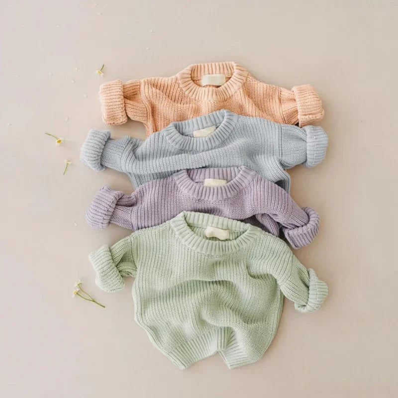 Four baby sweaters in pink, blue, purple, and green 